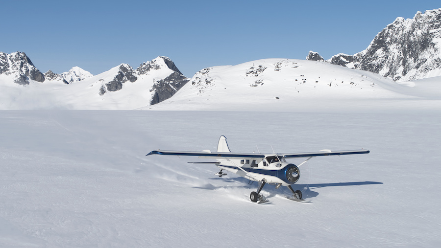 Small plane landing on snow in Alaskan mountains